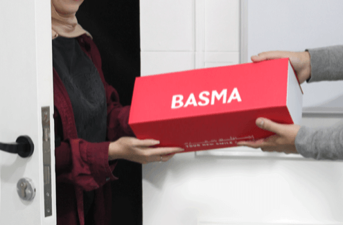 A patient receiving her aligners, aligner kit is in red with BASMA written in bold white letters